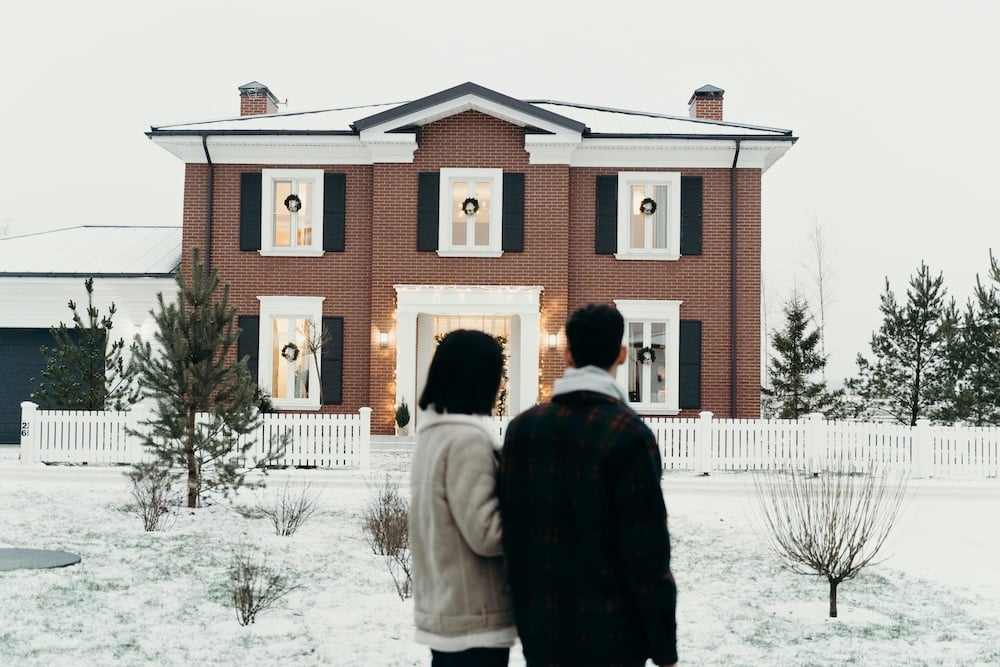 Happy couple standing outside an inviting home, admiring the welcoming facade and envisioning their future together. A moment of excitement and possibility.