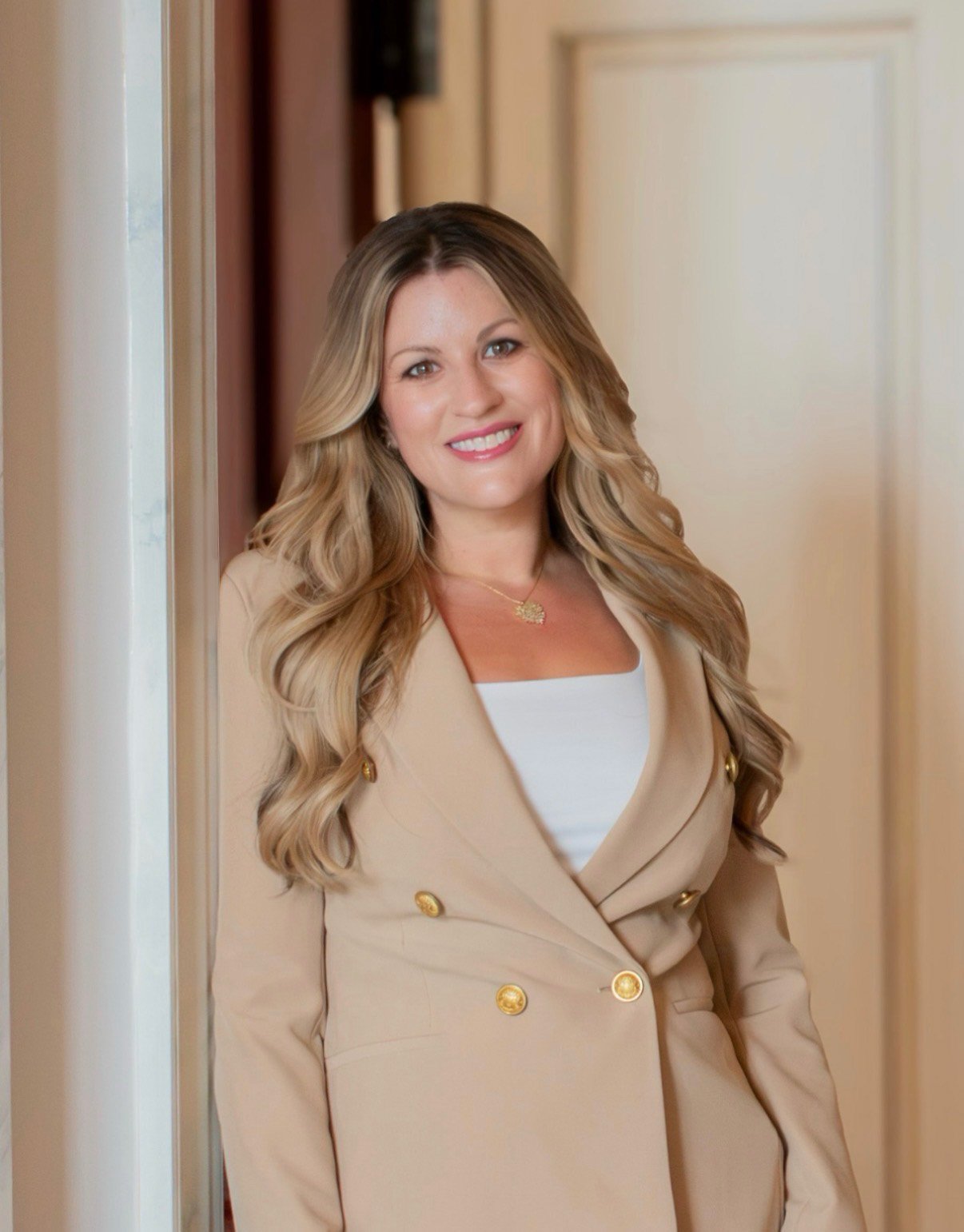 Jessica Ledbetter smiles in a beige blazer in a doorway.