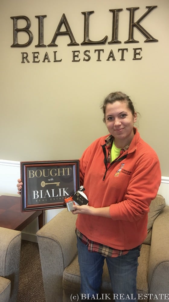 Katy holds a Bialik Real Estate home-purchase sign.