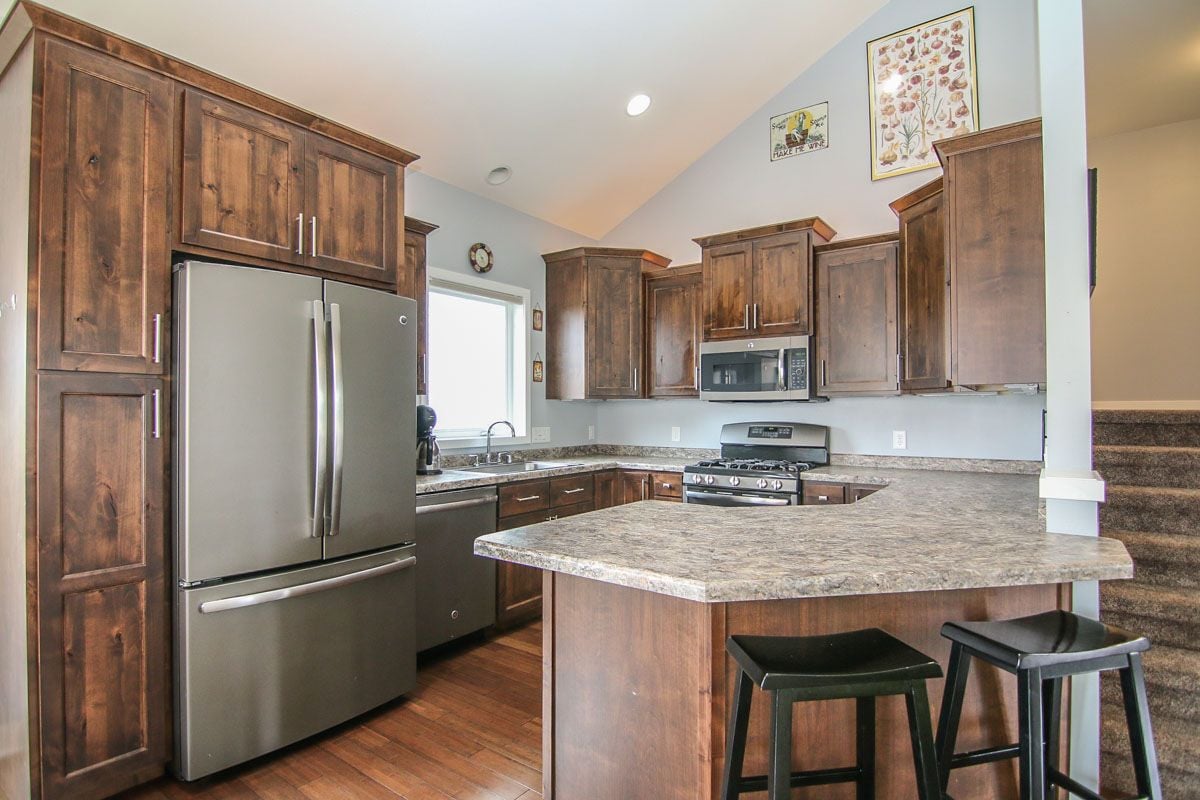 Kitchen with dark wood cabinetry, stainless steel appliances, and a large stone island with bar stools.