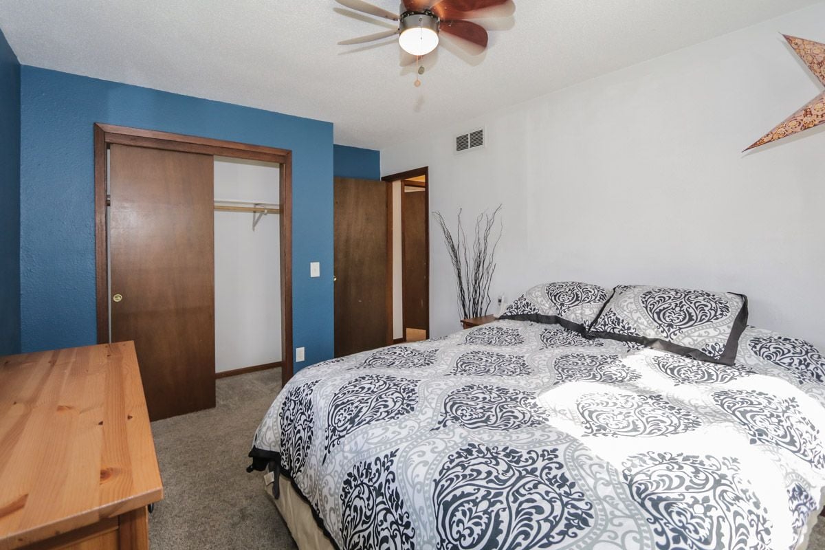 Bedroom with patterned bedding, a blue accent wall, and an open sliding closet.