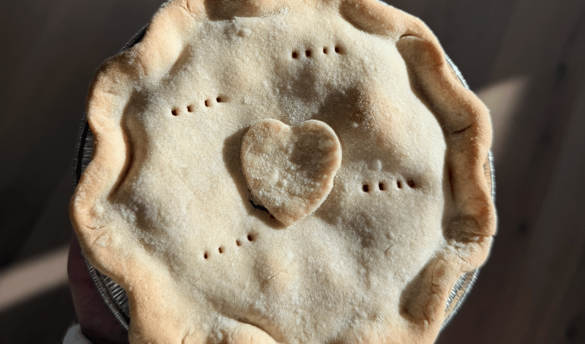 Unbaked pie with a heart-shaped pastry cutout and fork-prick decorations.