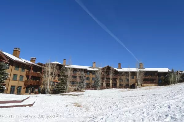 Multi-story wood-sided residential building with balconies and snow-covered grounds in Aspen.