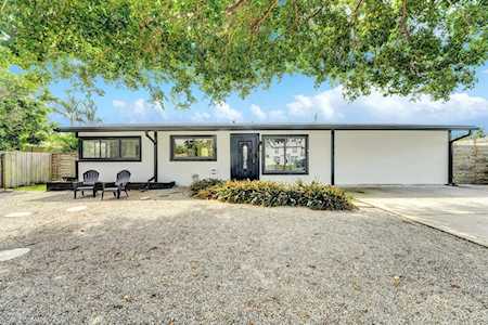 Modern single-story home with a broad gravel driveway beneath a large shade tree.