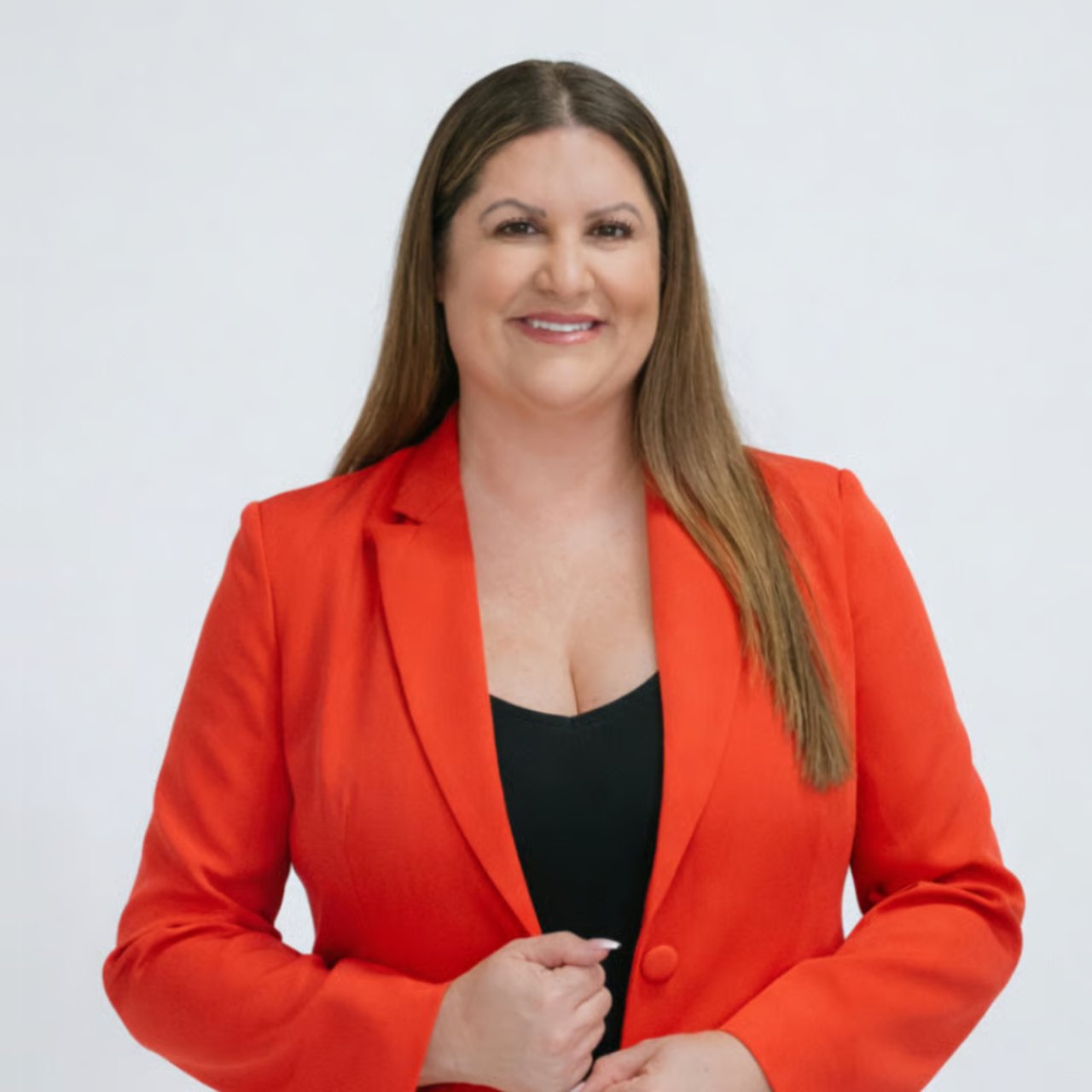 Smiling woman in a red-orange blazer poses for a real estate agent portrait.