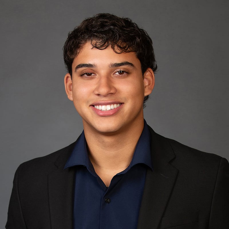 Alexander Fonseca smiling in a black blazer and navy shirt.