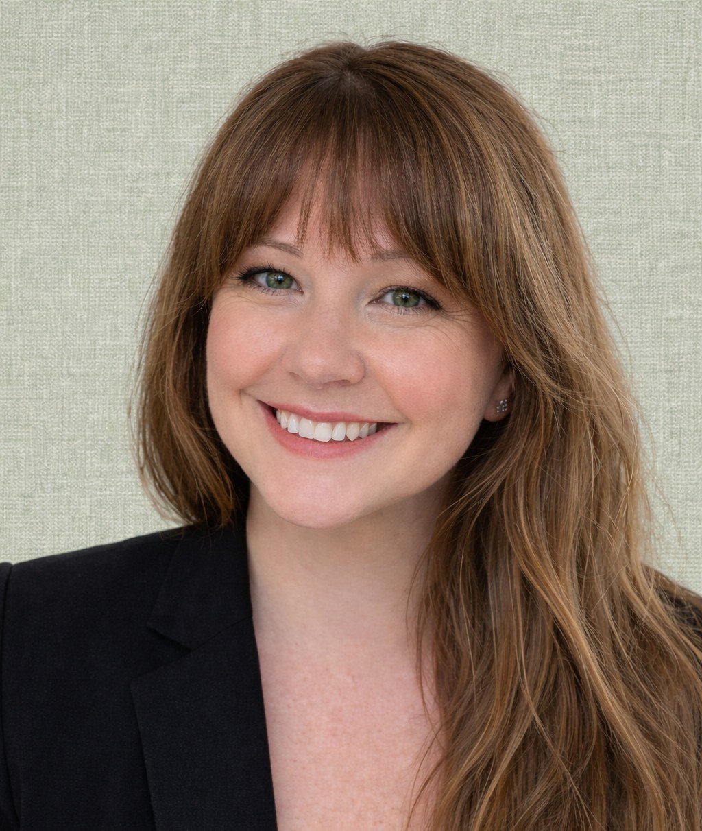 Sherri Moore smiling in a black blazer against a light textured backdrop.