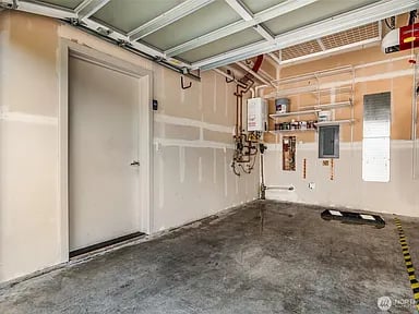 Vacant garage with unfinished drywall, exposed utilities, and a concrete floor.