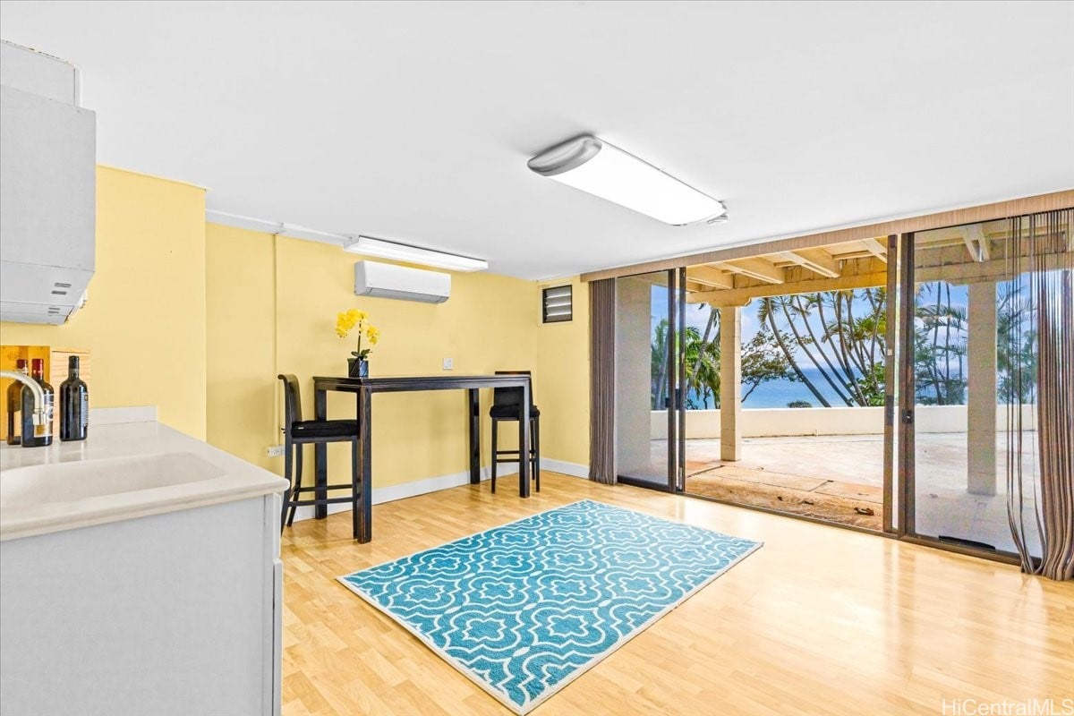 Dining area with a blue patterned rug and sliding doors opening to an ocean-view patio.