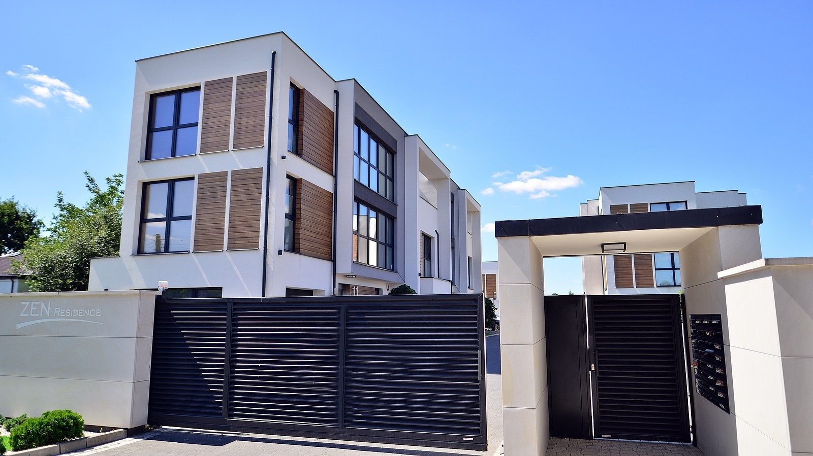 Modern Zen Residence with wood-accented facade and a tall black gated entrance.