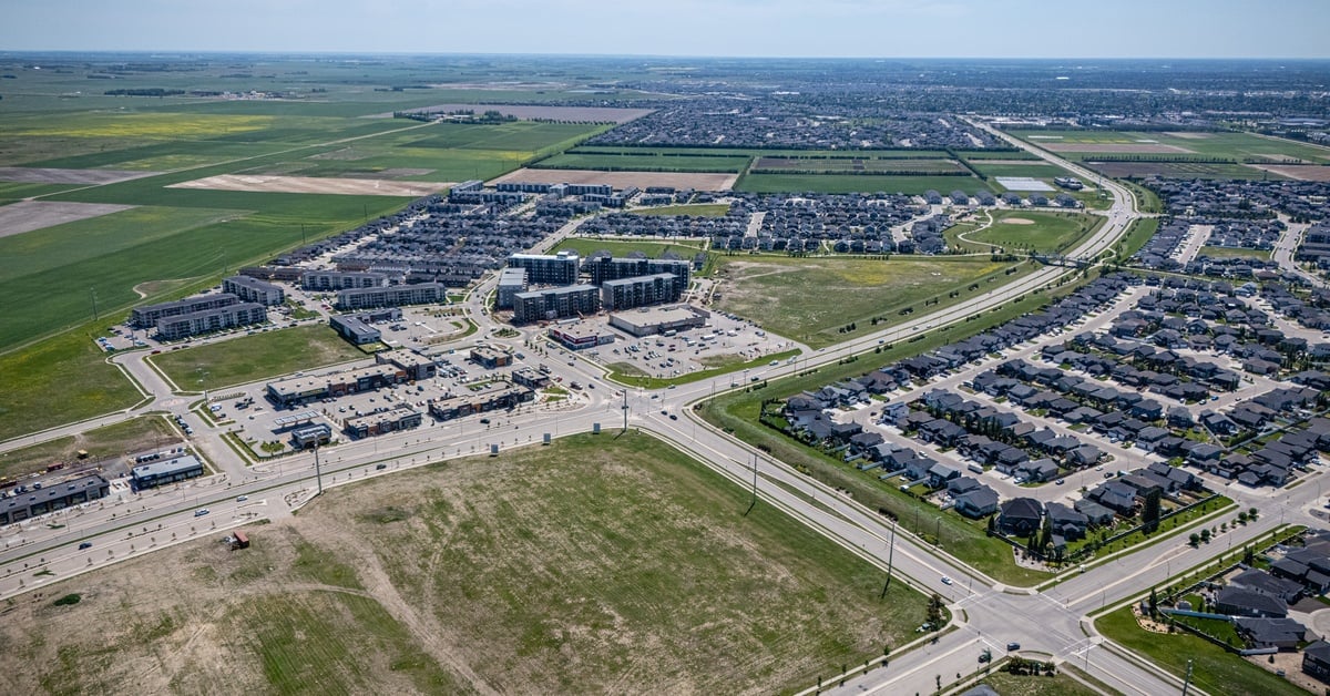 An aerial view of a residential development area with numerous houses with two large empty lots in the center.