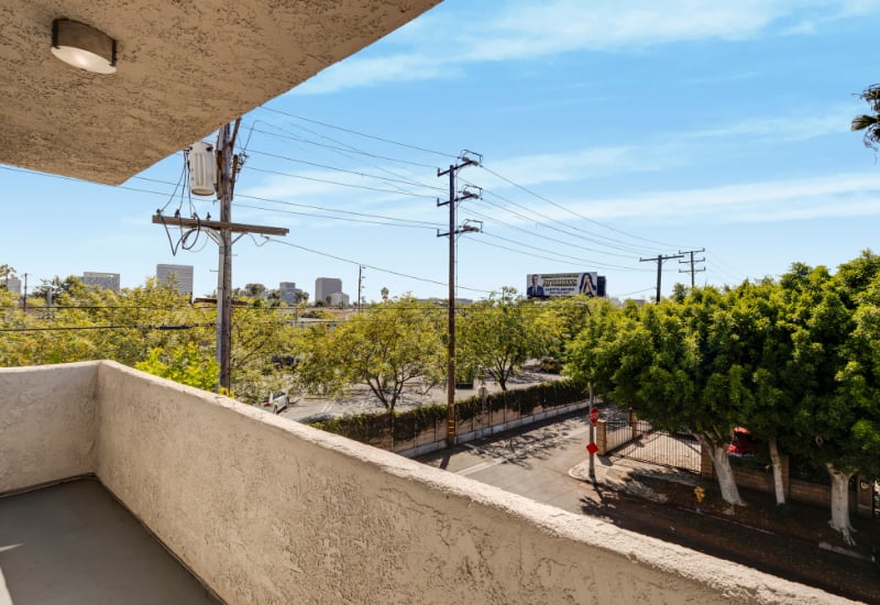 Balcony overlooking a tree-lined street, with utility wires and distant Los Angeles buildings.
