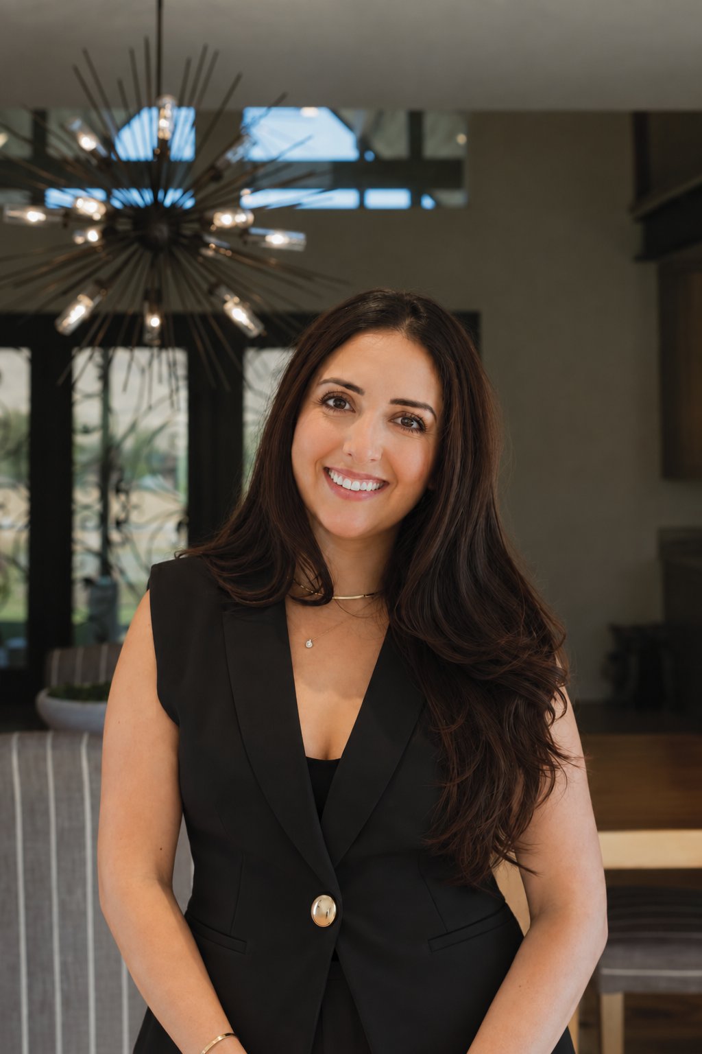 Salma Pattni smiling in a black sleeveless blazer indoors.