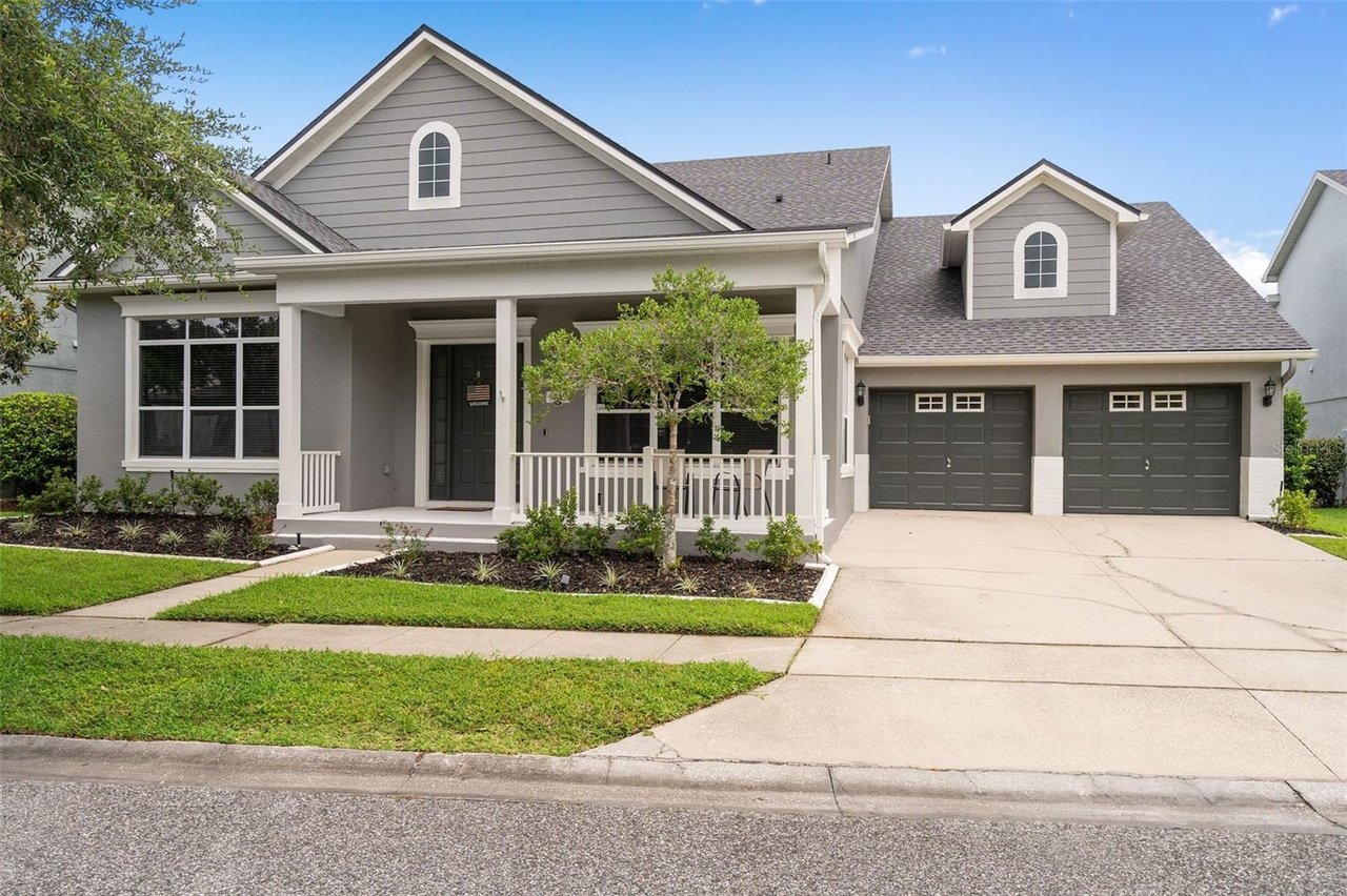 Gray two-story house with a covered front porch, twin garage doors, and landscaped lawn.