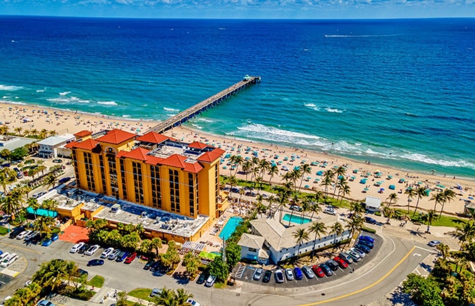 Aerial view of Deerfield Beach with its pier, sandy shore, and beachfront hotel.