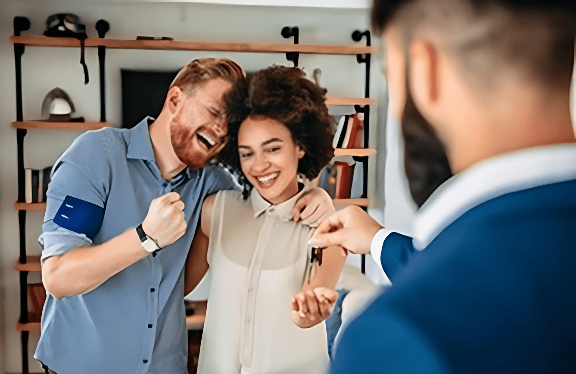 A couple celebrates with their real estate agent in a home.