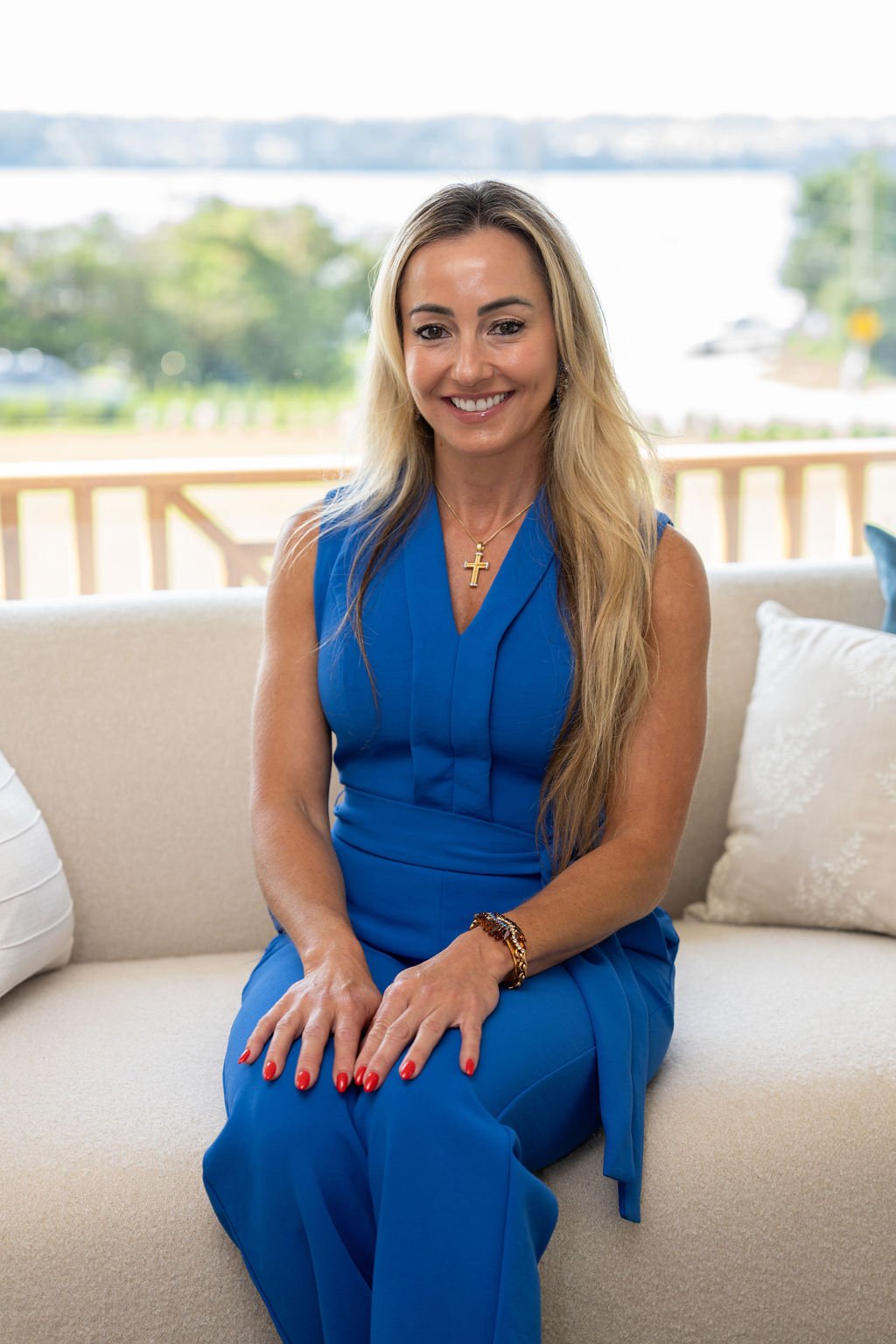 Liana D'Amico seated on a sofa in a bright blue dress.