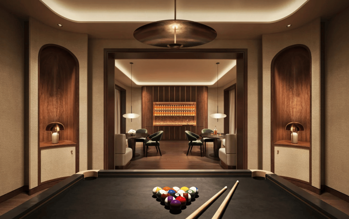 Billiards room with a pool table and racked balls beside a wood-paneled lounge.