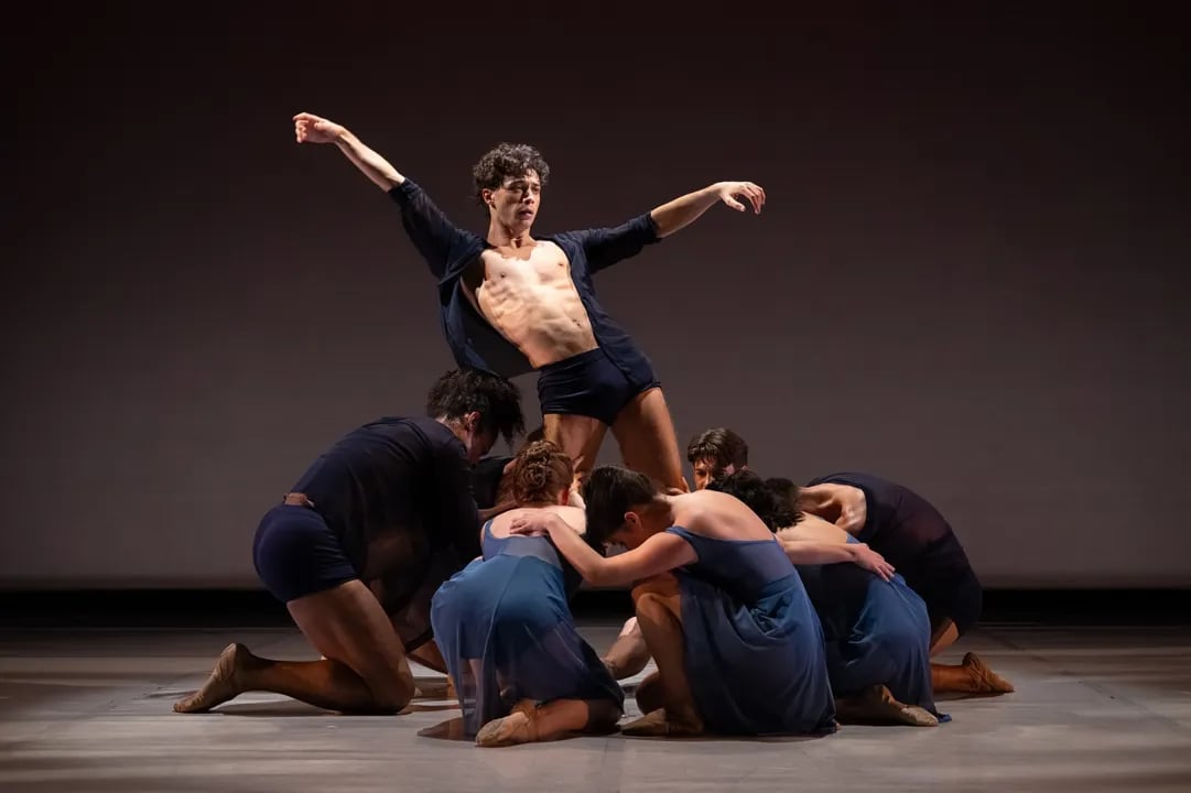 Performers from Smuin Contemporary Ballet executing a powerful, collective contemporary dance piece on a dramatically lit stage in San Francisco.
