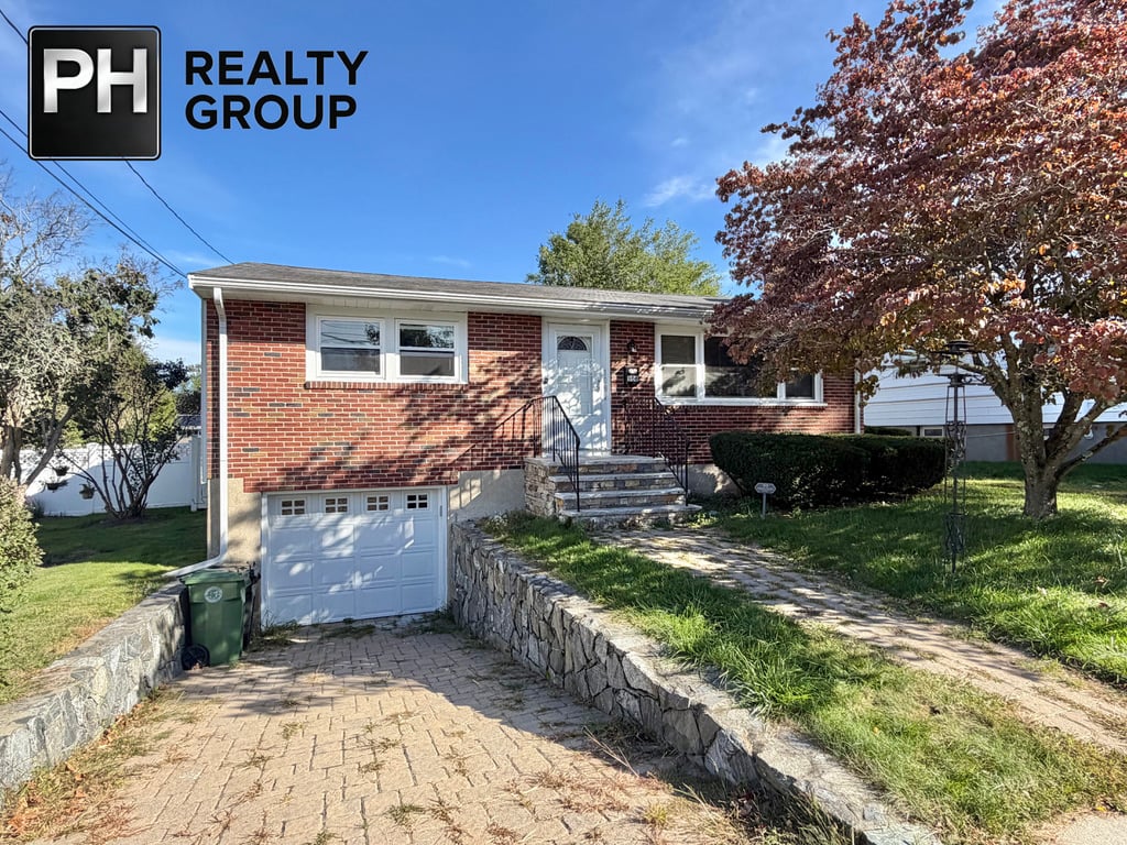 Single-story brick house with an attached garage, stone driveway, and an autumn tree.