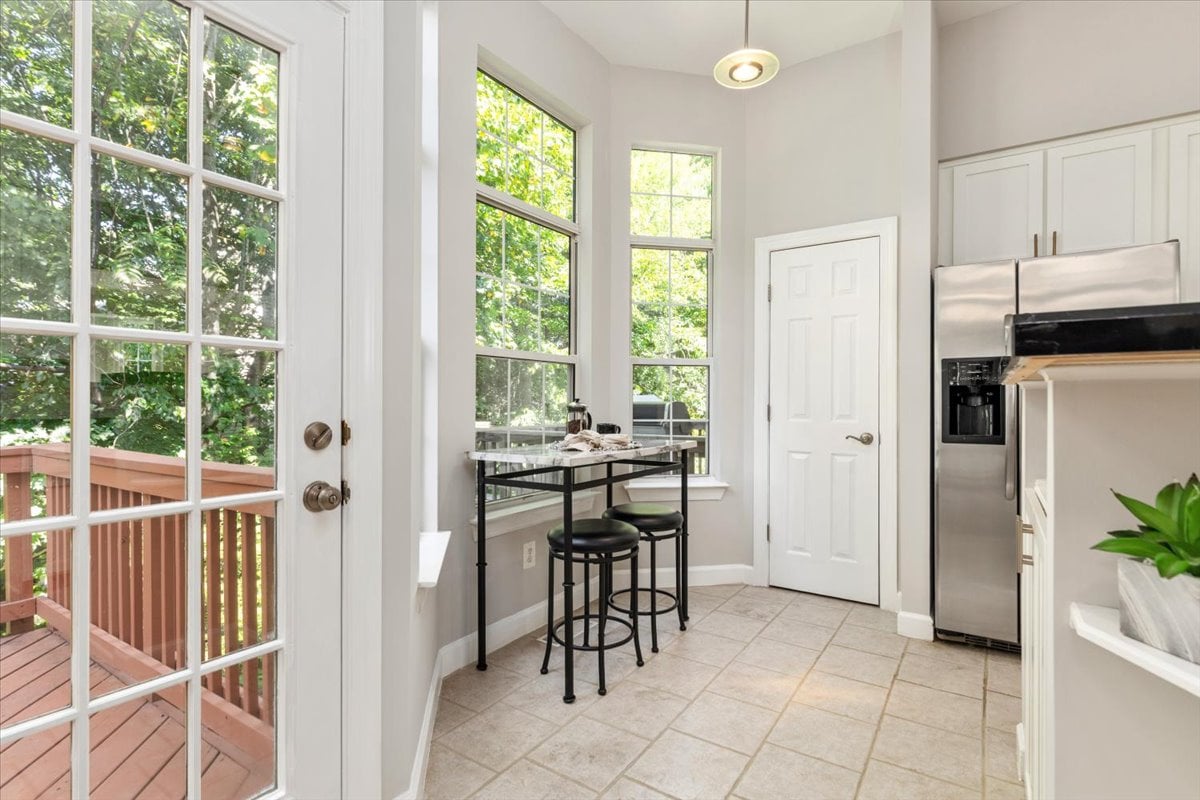 Kitchen with tall windows, stainless steel appliances, and a glass door opening onto a deck.