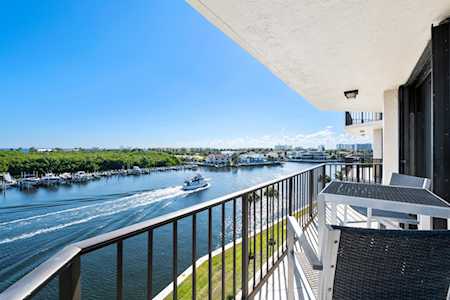Waterfront apartment balcony with black railing and patio furniture overlooking a canal with passing boats.