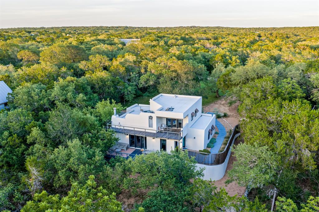 Modern white home with broad decks nestled among dense trees.