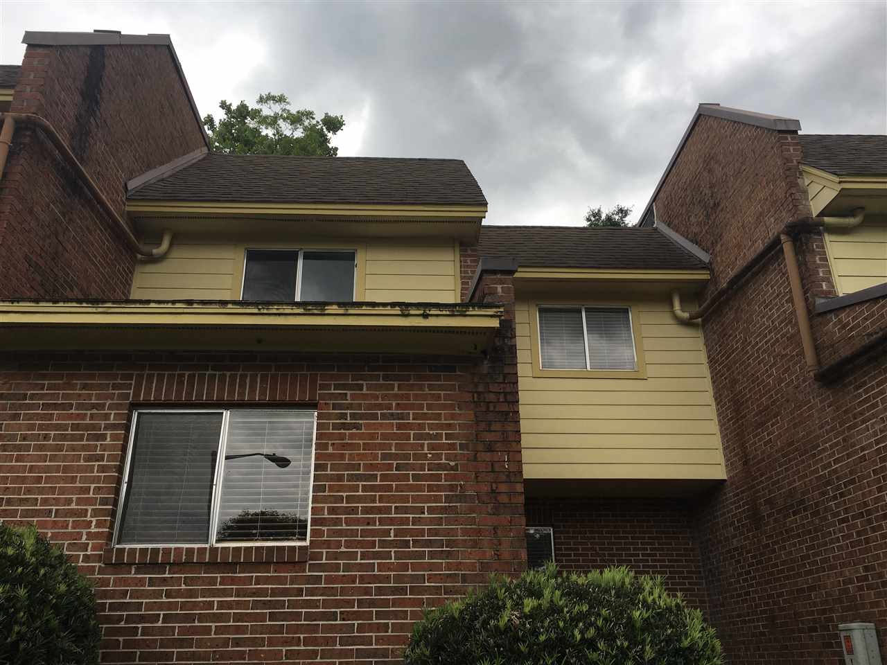 A brick house featuring a large window and a sloped roof, showcasing a classic architectural design.