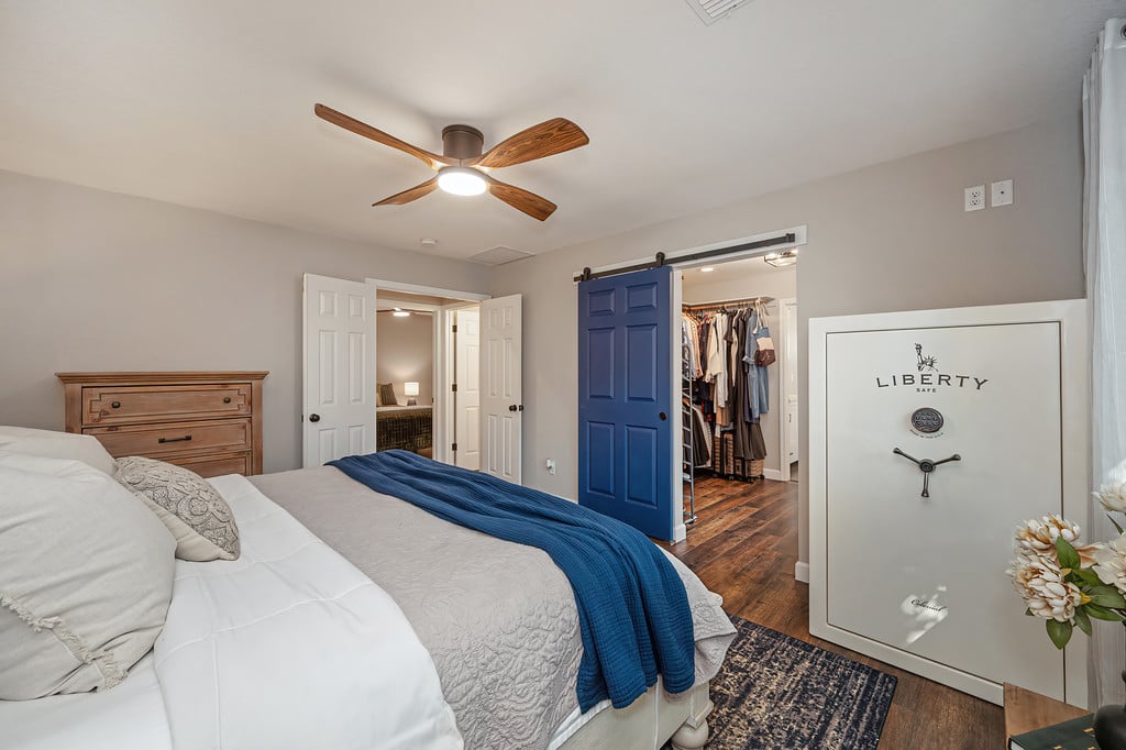 Furnished bedroom with a blue sliding barn door, walk-in closet, and large Liberty safe.
