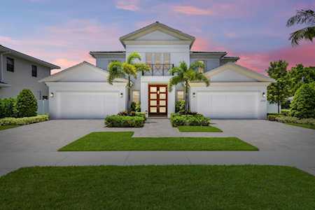 Two-story home with twin garages, a central entrance, and palm landscaping at dusk.