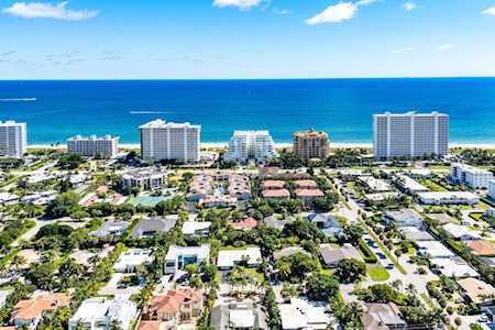 Aerial view of a leafy coastal neighborhood, high-rise buildings, and blue ocean.