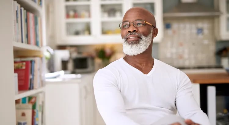 A photo of a smiling older man with a beard and glasses, dressed in a white shirt, likely used in an article or a piece discussing economic or personal finance topics.