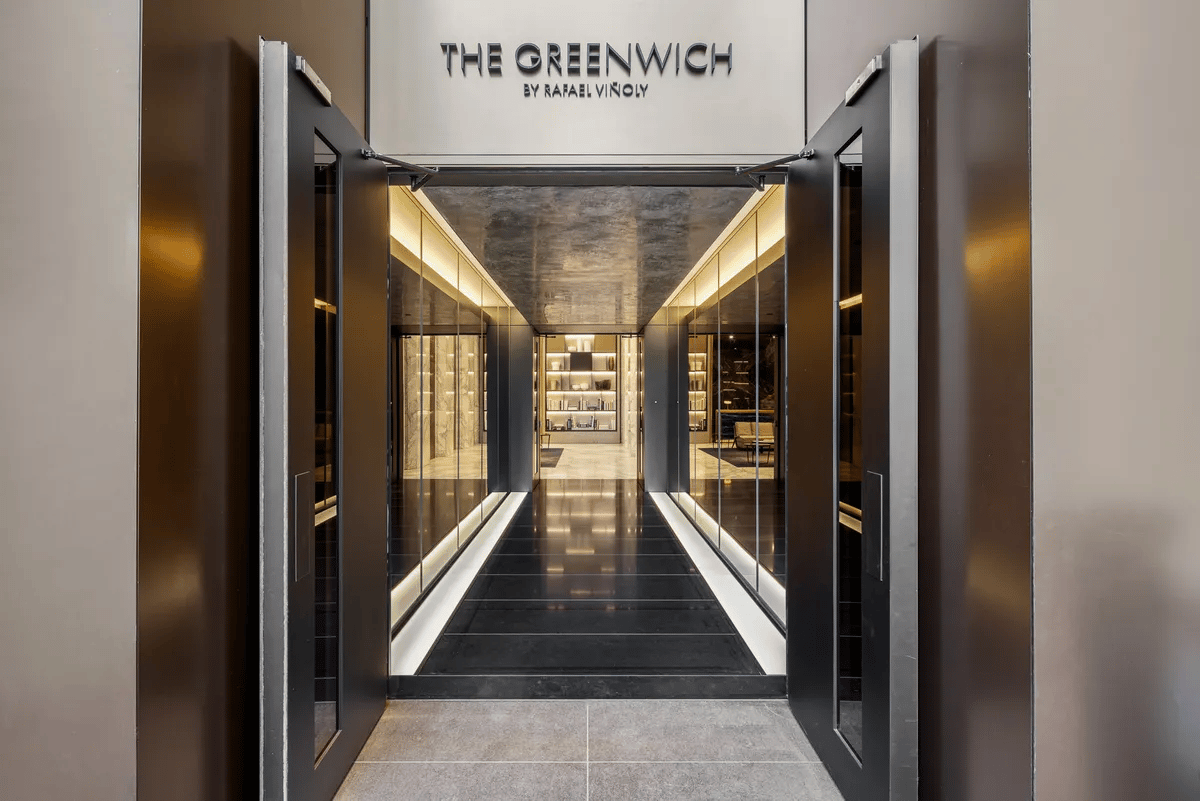 The Greenwich entrance opens onto a modern lobby corridor with dark flooring and warm lighting.