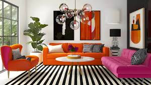 Colorful modern living room with a pink sofa, orange chairs, and a bold striped rug.