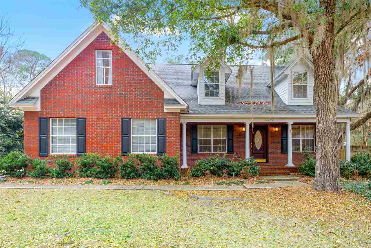 A brick home surrounded by a spacious front yard, showcasing a well-maintained landscape and inviting atmosphere.