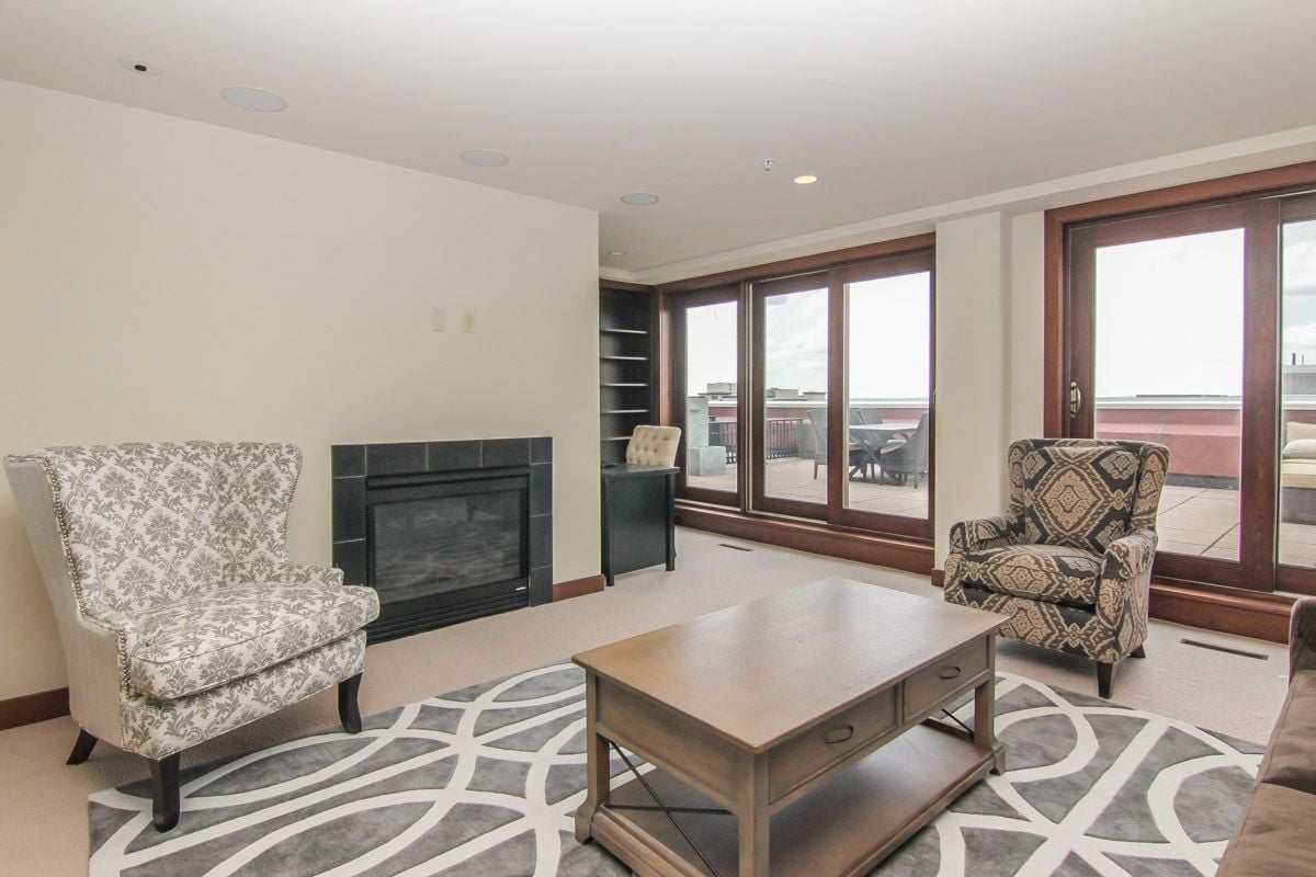 Living room with a tiled fireplace, patterned armchairs, and glass doors to a terrace.