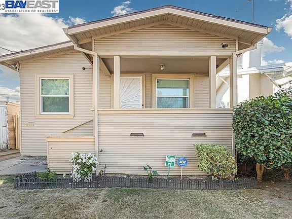 Beige-sided Oakland home with a broad covered porch and prominent gabled roof.