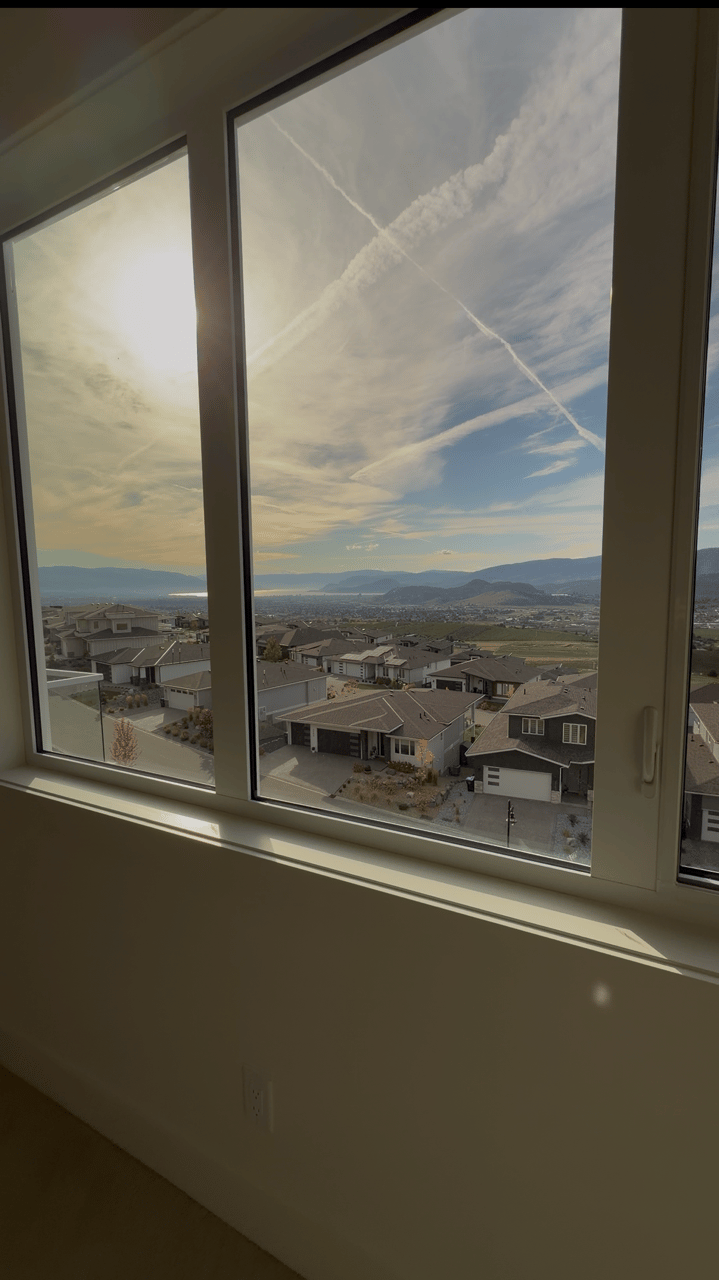Residential development and distant mountains seen through large interior windows.