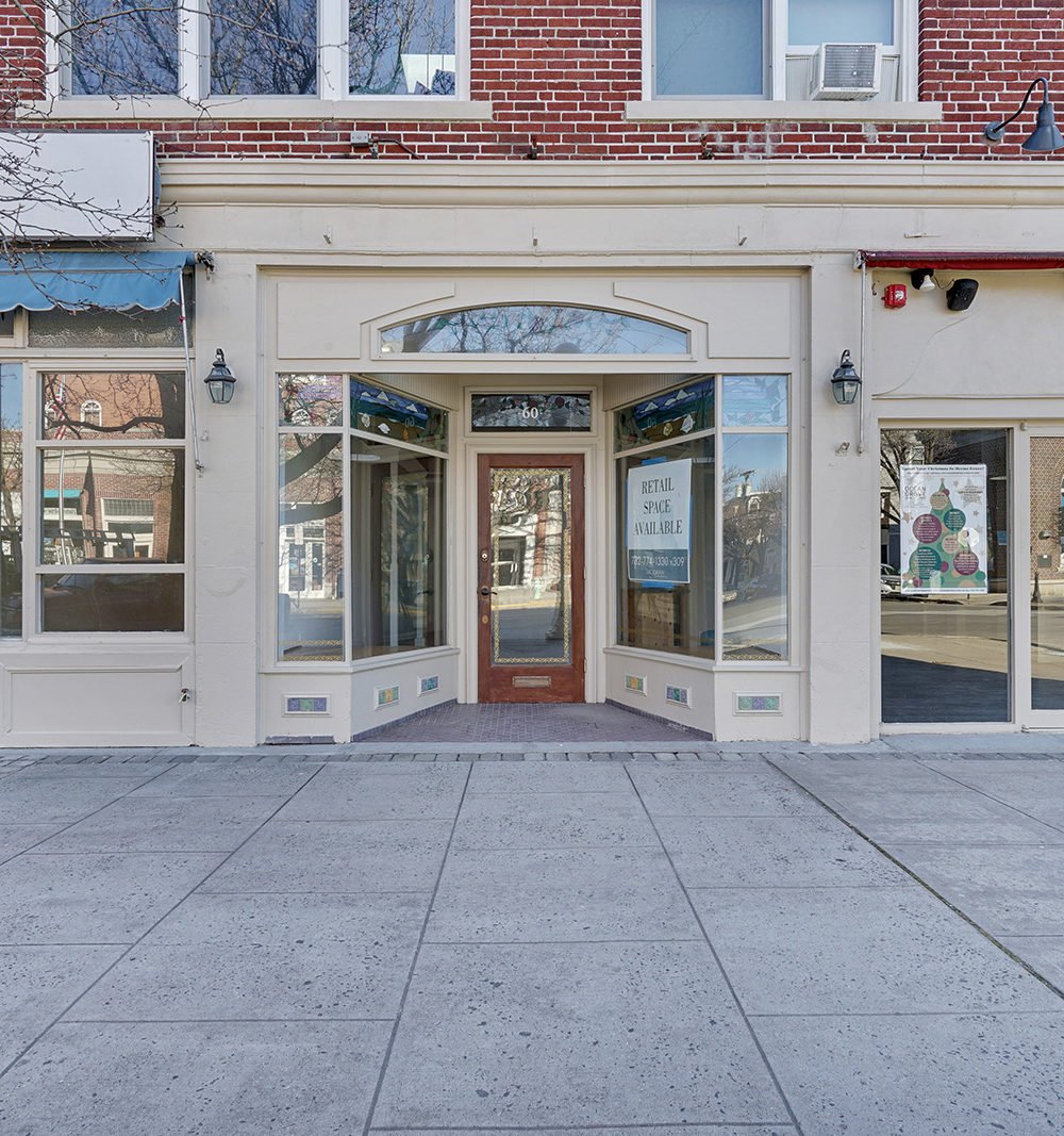 Vacant retail storefront with a recessed wooden entry and red brick facade.