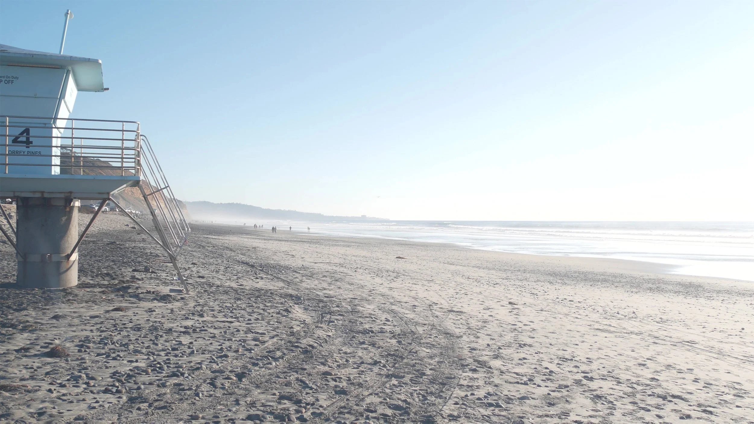 Torrey Pines beach with a lifeguard tower marked 4 and a hazy coastline.