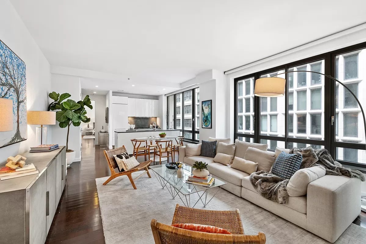 Open-plan apartment living room with a large sectional sofa and floor-to-ceiling windows.
