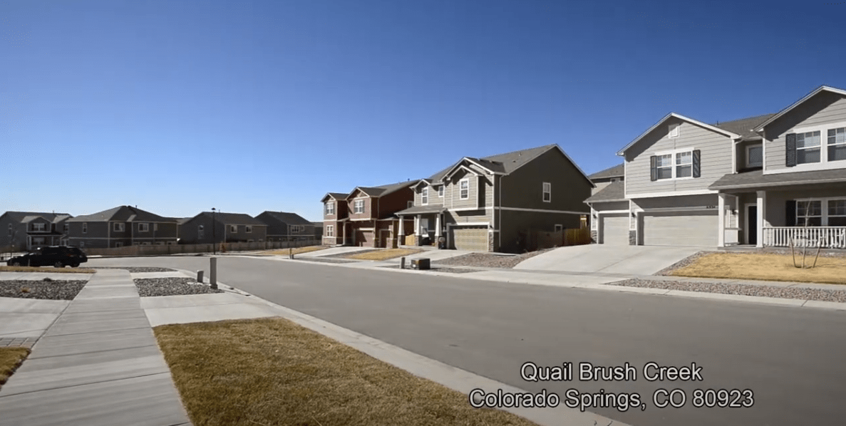 Quail Brush Creek residential street with rows of two-story homes and broad sidewalks.