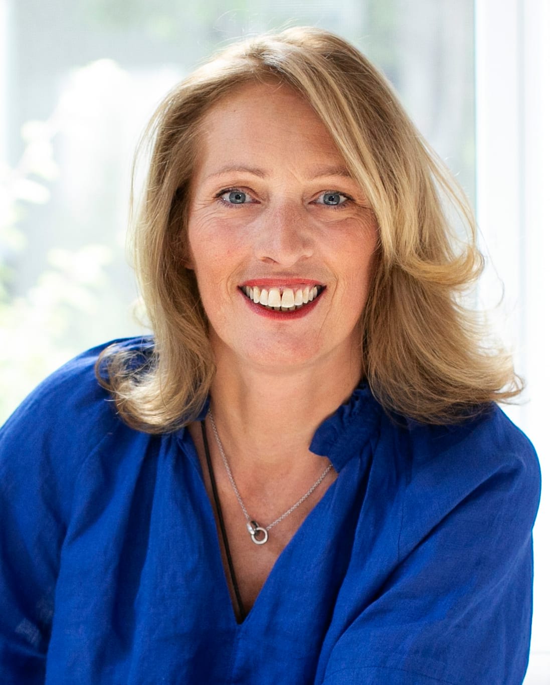 Real Estate Agent Sandrine Deschaux wearing a blue blouse and a necklace.