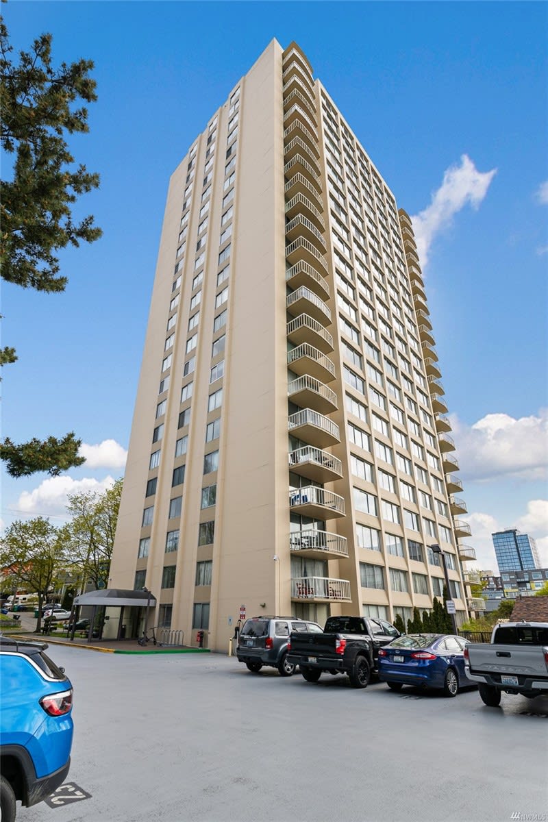 Sunlit upscale condo building with a parking lot, offering modern city living.