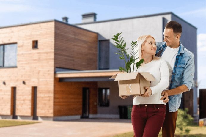 happy couple with their new house at the background