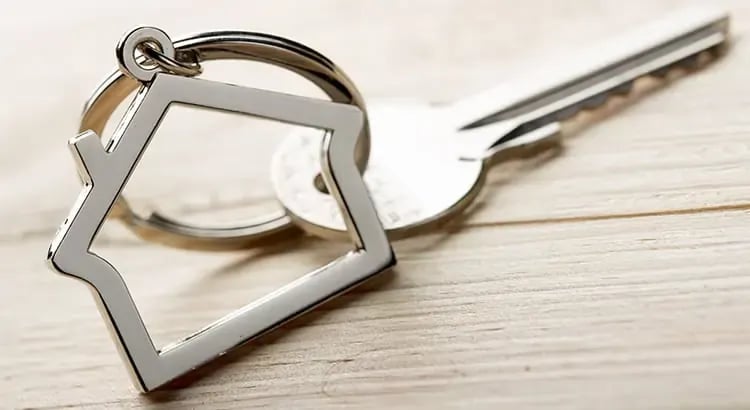 a set of house keys with a house-shaped keychain, symbolizing home ownership or rental.