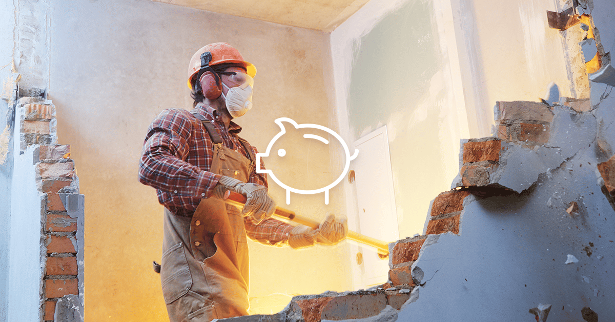 Construction worker demolishing an interior wall beside a white piggy bank outline.