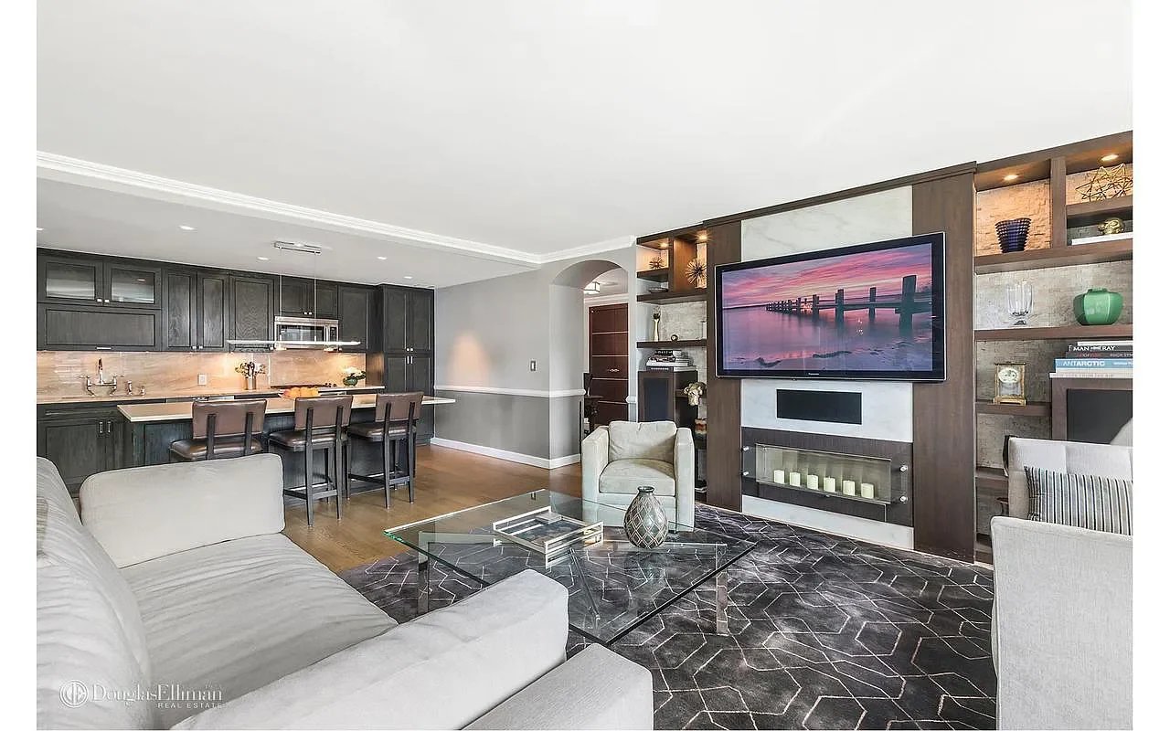 Open-plan living room and kitchen with dark cabinetry and a built-in fireplace and media wall.