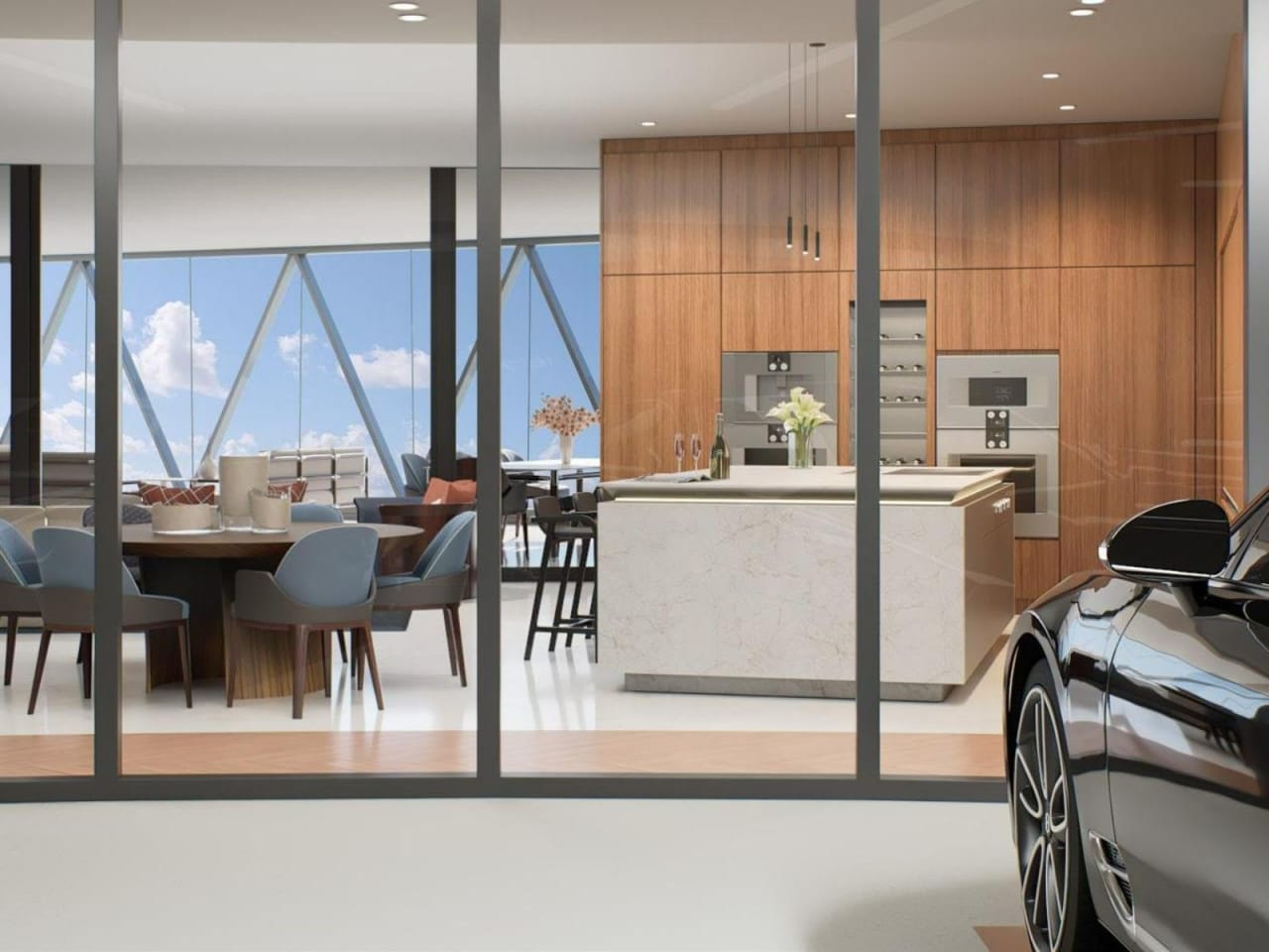 Open-plan kitchen and dining area with wood cabinetry, a stone island, and a car in the foreground.