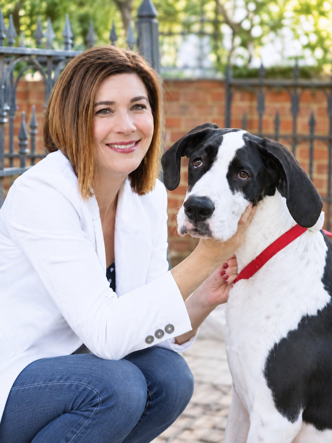 Lisa Fanucci-Dario crouches beside a large black-and-white dog outdoors.
